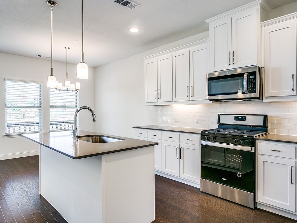Kitchen has gas range and opens to living and dining areas.