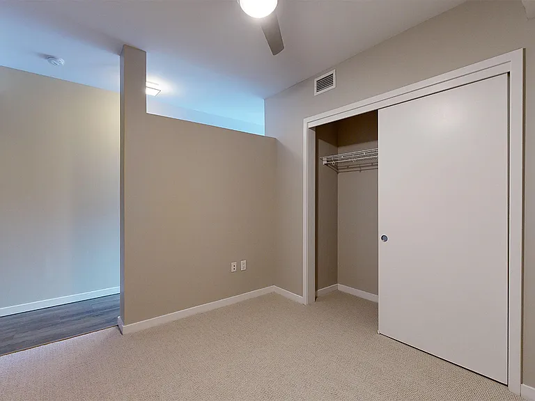 Spacious apartment bedroom with plush carpet flooring.