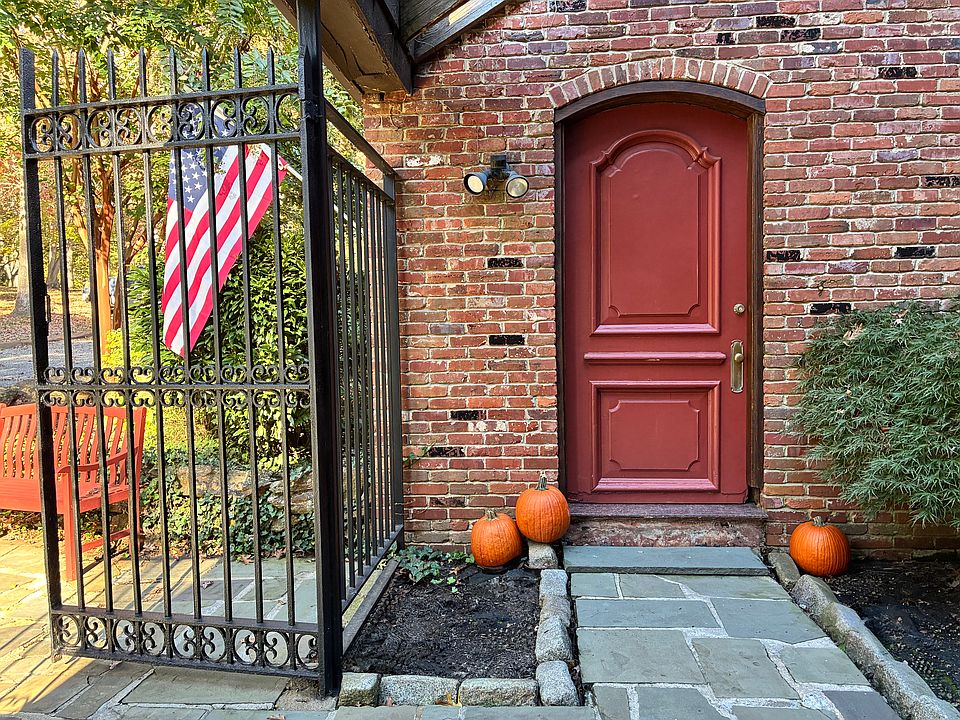 A warm welcome home. The charming brick entry features a classic red door, natural stone pathway, and festive seasonal touches.