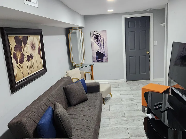 Comfortable shared living area with tiled floors, recessed lighting, seating, and a TV setup for relaxing or streaming.