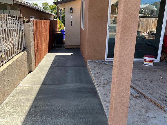 The background shows a detached garage which is currently a garage conversion. There is a vinyl fence dividing the buildings now
