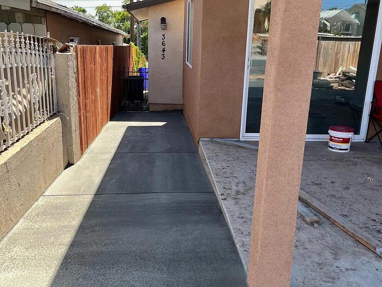 The background shows a detached garage which is currently a garage conversion. There is a vinyl fence dividing the buildings now