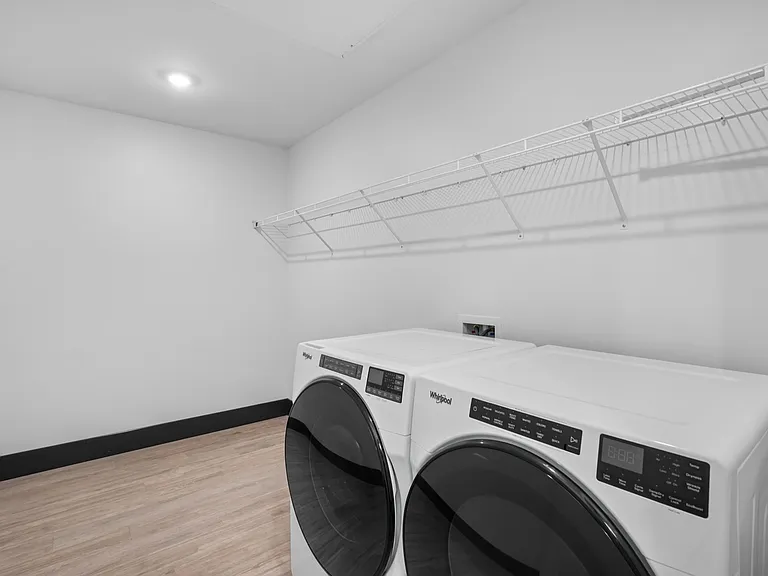 Modern laundry room with sleek washer and dryer, featuring ample shelving and clean design. Modern laundry room with sleek washer and dryer, featuring ample shelving and clean design.