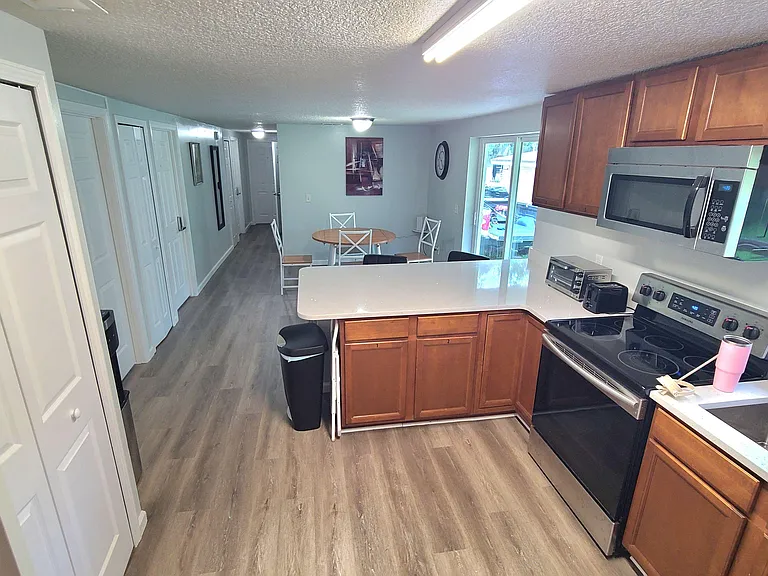 Open kitchen with ample cabinet storage, generous counters, and stainless appliances, flowing into a dining nook by windows.