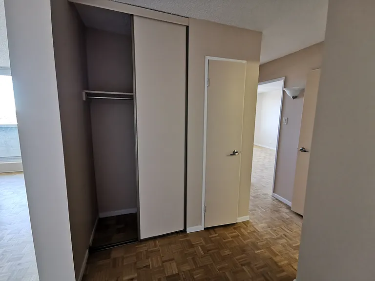 Main entrance with view towards coats closet, storage closet and bedrooms.