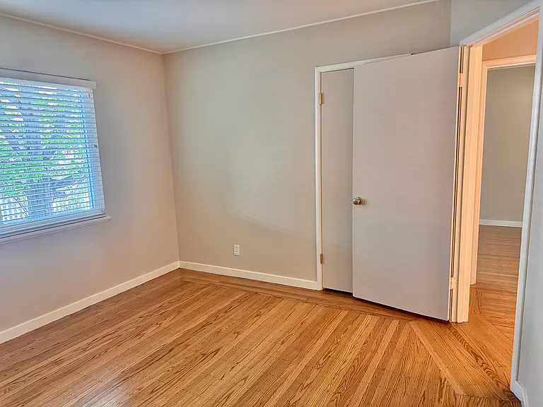 The secondary (northeast) bedroom enjoys dappled light and offers a peaceful view of the mature maple outside.