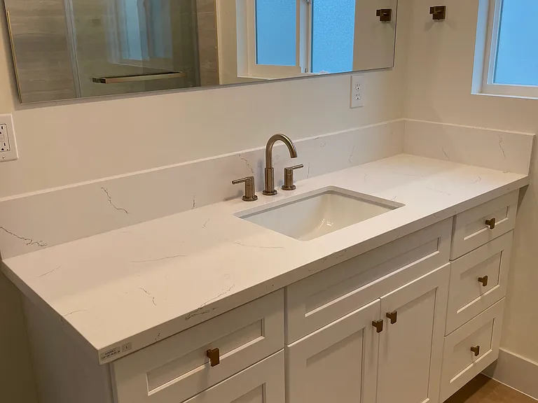 Bathroom 1 - custom-designed vanities, Delta gold hardware, large-format tile, and modern rainfall showers