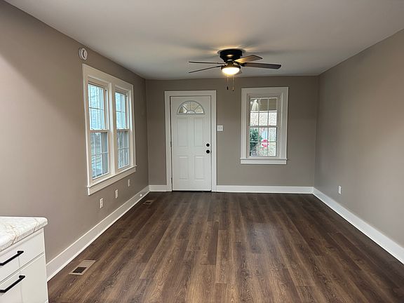Bright and welcoming front living room featuring modern wood-look plank flooring and a contemporary ceiling fan. This open, light-filled space flows directly into the newly renovated kitchen.