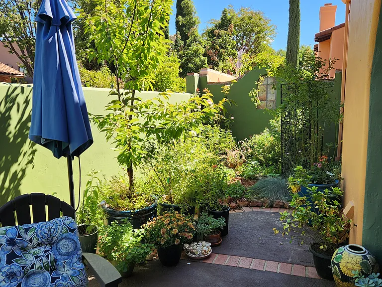 The backyard is a delightful, walled garden full of flowering plants, and provides both a covered sitting area and lovely strolling path.