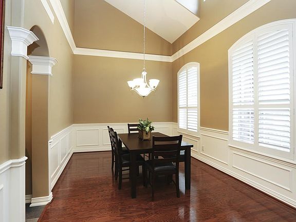 Dramatic 2 story dining room has attractive decorative moldings and gleaming hardwood flooring.