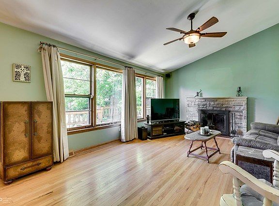 Living room features large windows overlooking the huge yard, woodburning fireplace and hardwood floors