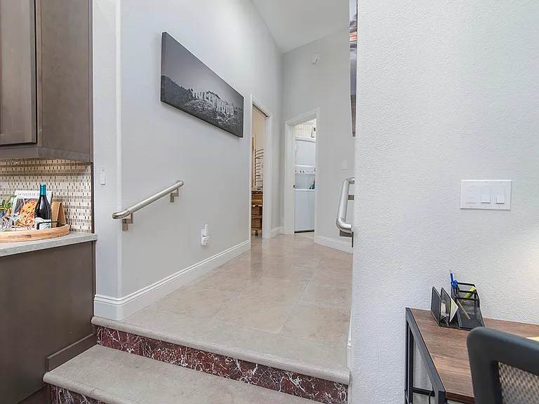 Hallway to the bedrooms with two steps up from the main lounge area and full kitchen. Handrails are mounted on the wall on either side of the steps.