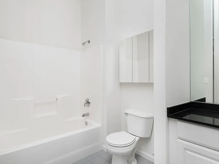 Tile-floored and granite modern bathroom at Victory Building Apartments
