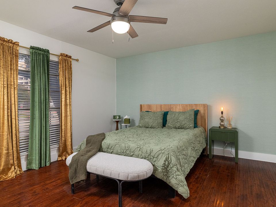Rest in a calming bedroom with soft green tones, warm lighting, and a cozy bench at the foot of the bed. Enjoy a large TV, stylish dresser, and easy access to a spacious walk-in closet for a relaxing, comfortable stay.