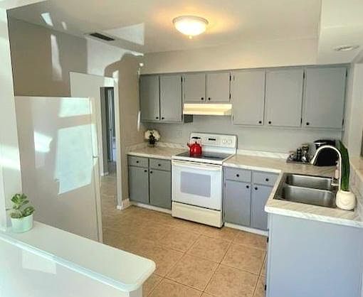 Freshly painted and updated kitchen with fridge, flat top electric stove and range hood.