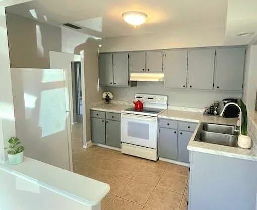 Freshly painted and updated kitchen with fridge, flat top electric stove and range hood.