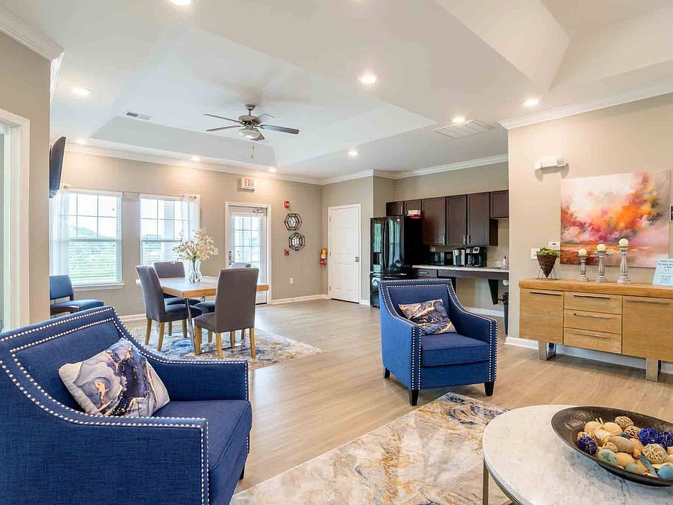 Elegant resident clubhouse with modern furnishings, dining table, lounge seating, and full kitchenette at Cedar Terrace Apartments.