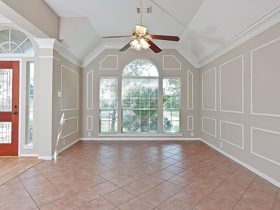 Located just off the foyer is this beautiful formal living area complete with high ceilings, crown & picture frame mouldings, ceramic tile flooring, a ceiling fan with a light fixtures and large windows with blinds overlooking the front yard.