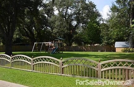 Large yard with fence and storage shed.
