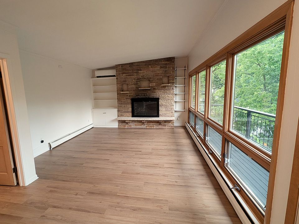 Expansive living room with floor-to-ceiling windows facing Minnehaha Creek, and a wood-burning fireplace.