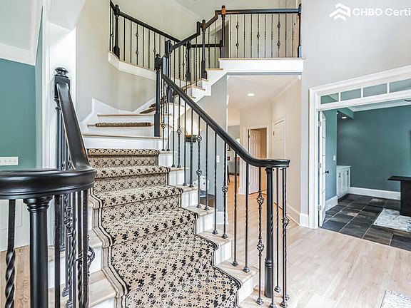 Sunlit front foyer featuring 1 of 2 elegant staircases