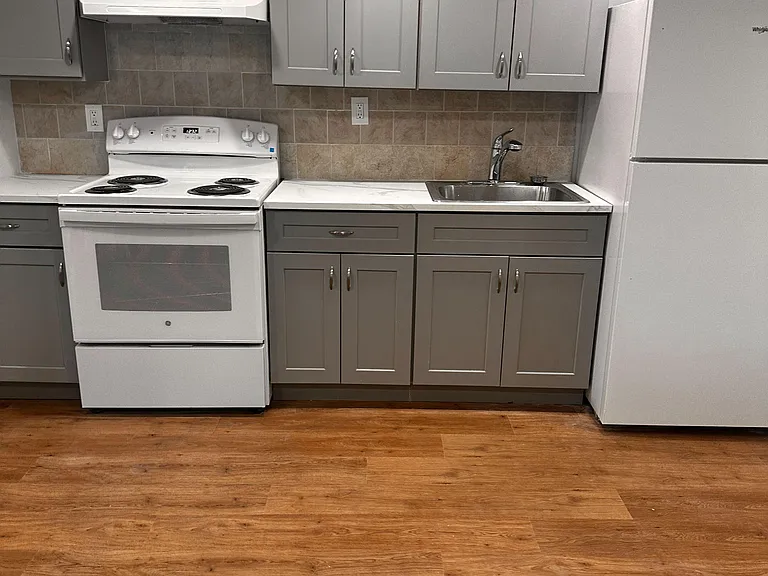 Efficient kitchen setup with ample cabinet storage, tile backsplash, and full-size range, refrigerator, and sink.