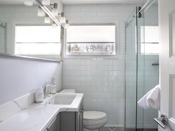 New renovated bathroom with walk in glass shower with spray handle and tiled shower. New toilet, floating custom vanity with quartz countertop and large mirror.