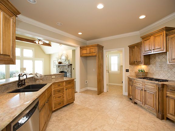 Jenn-Air gas cooktop with downdraft is accented by decorative tumbled marble accent. Oversize pass through Laundry Room features utility sink, storage cabinets and plantation shutters.