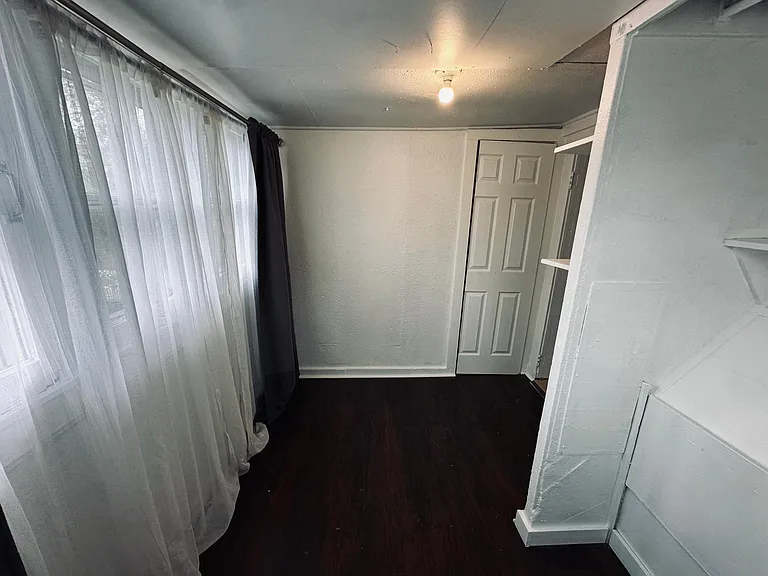 Bedroom, black out curtains and sheer curtains provided, light filled room. Laminate wood floors. 
East facing windows.