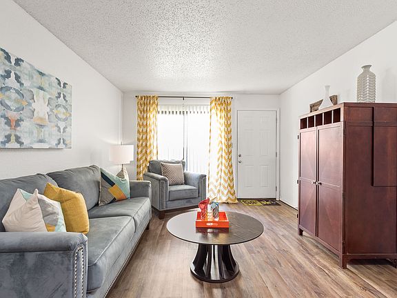 Living Room View with Hardwood Floors and Large Window - Raindance Apartments