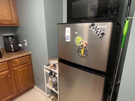 Kitchen area - medium sized refrigerator with microwave on top
