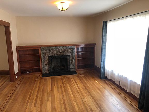 Living room with refinished hardwood flooring + built-ins.