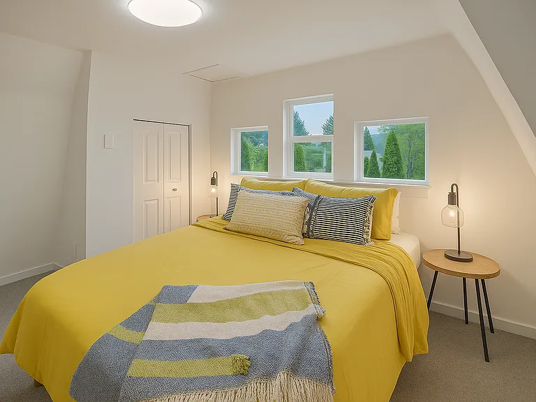 Wake up to lush treetop views from this vibrant bedroom featuring a cloud-soft queen bed and playful pops of yellow. A bright, cheerful space to start and end your day