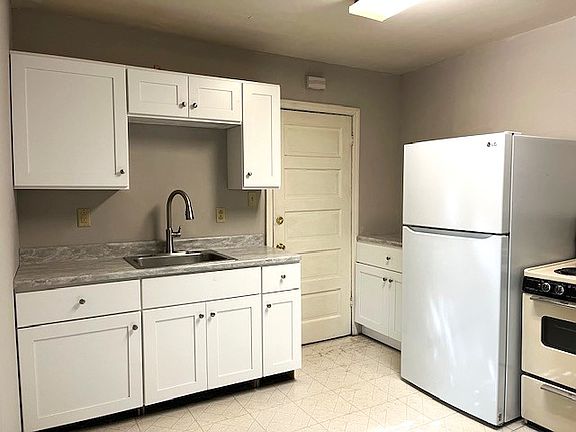 kitchen with new cabinets, countertops, refrigerator, and faucet