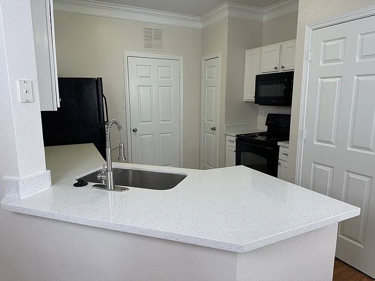 Modern kitchen with sleek quartz countertops, undermount sink, and contemporary black appliances, perfect for stylish living. Modern kitchen with sleek quartz countertops, undermount sink, and contemporary black appliances, perfect for stylish living.