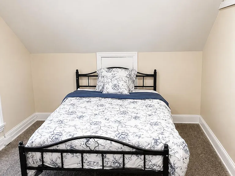 Carpeted bedroom with a full-size bed, recessed lighting, and a compact window for natural light.