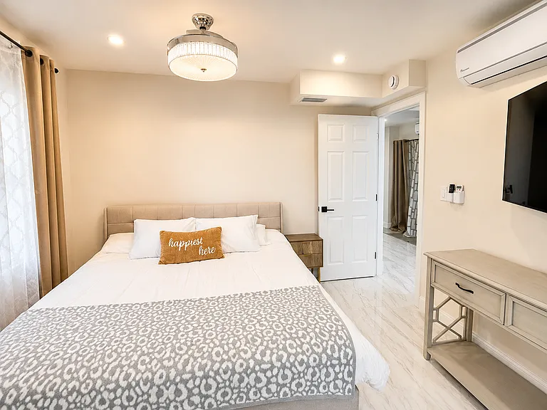 Private guest suite bedroom with king bed, smart TV, closet space, ensuite-style bathroom access, and a comfortable setup for couples, in-laws, or colleagues.