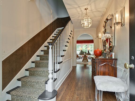 The foyer with coat closet showcases new designer lighting fixtures, wall paper and stair runner