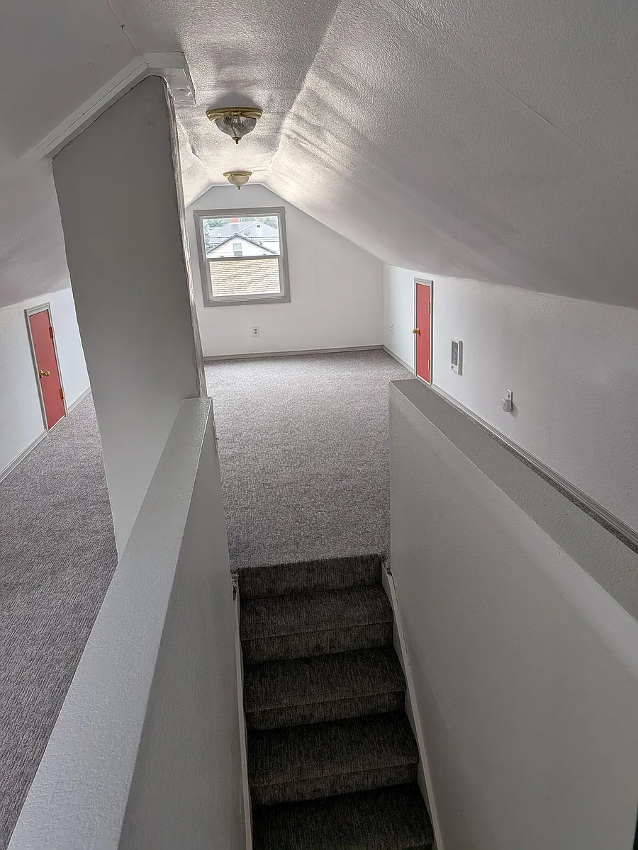 Photo 2 of 9 - SE 140th Ave - Portland, OR Carpeted upper-level landing with sloped ceilings, overhead lighting, and a window bringing in natural light. - SE 140th Ave