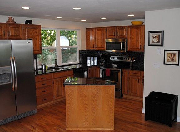 Modern kitchen with wood cabinets, hardwood floors, center island, and includes dishwasher, microwav