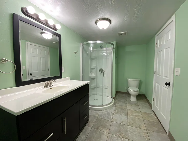 Modern bathroom with mint green walls, sleek vanity, and elegant glass shower enclosure. Modern bathroom with mint green walls, sleek vanity, and elegant glass shower enclosure.