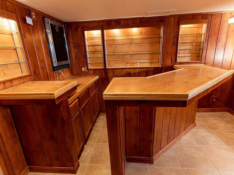 Bar with small fridge, sink, and plenty of storage.