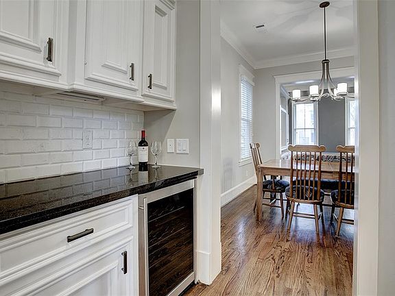 ButlerÃ¢s pantry off the kitchen has granite counters, decorative tile backsplash, and a beverage chiller.