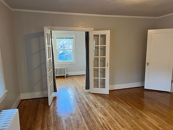Living room and 2nd bedroom with its view, french doors, and wood floors.