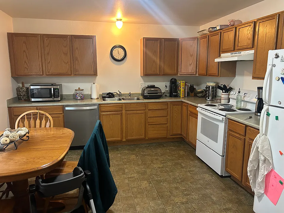 Kitchen with lots of cupboards. Refrigerator, stove/oven, dishwasher. Large window to the left overlooking porch area. Room for a kitchen table.