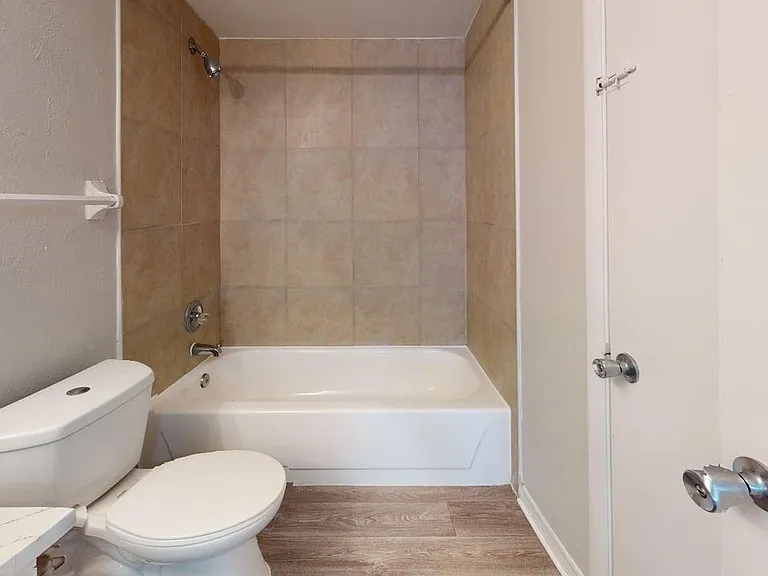 Modern bathroom featuring a sleek white bathtub, tiled walls, and a classic toilet, offering a clean and inviting space. Modern bathroom featuring a sleek white bathtub, tiled walls, and a classic toilet, offering a clean and inviting space.