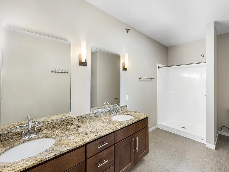 Modern bathroom featuring elegant granite countertops, dual sinks, large mirrors, and a spacious shower area. Modern bathroom featuring elegant granite countertops, dual sinks, large mirrors, and a spacious shower area.