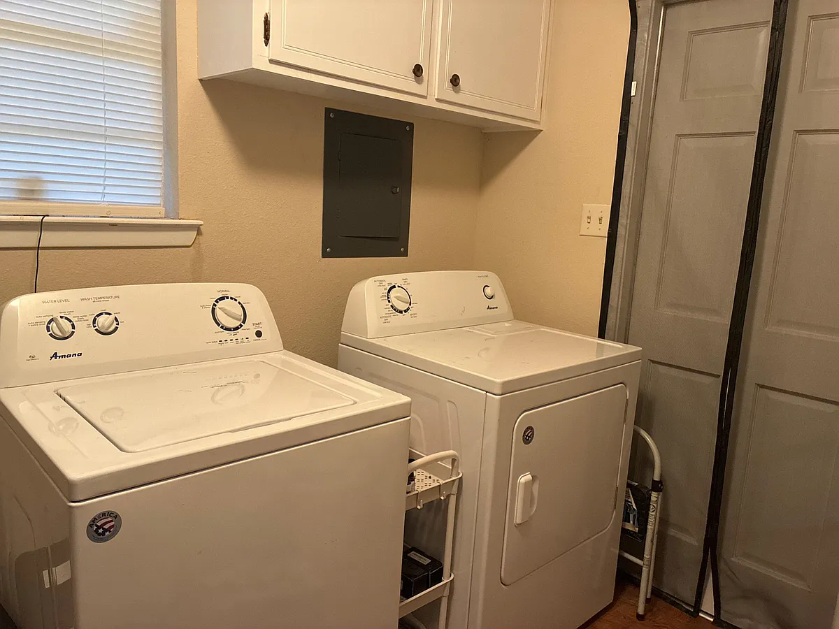 Dedicated laundry area with full-size washer and dryer, overhead cabinetry, and convenient access near the hallway. - Foster Rd