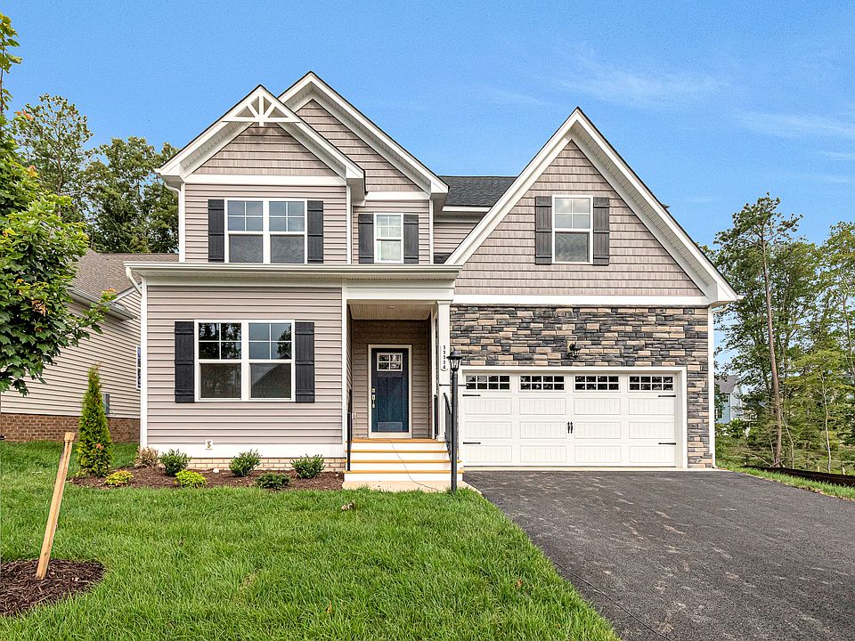 Two-story Somerset Hill home with gray siding, stone accents, two-car garage, and lush grass surroun