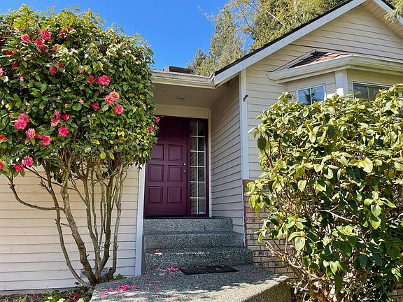 Front door with gorgeous rhododendron bushes on both sides of walkway.